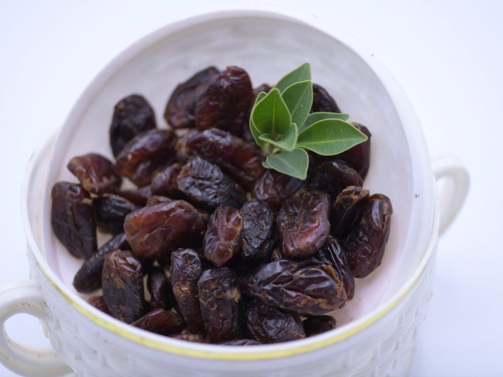 Dates served in a white cup with leaves