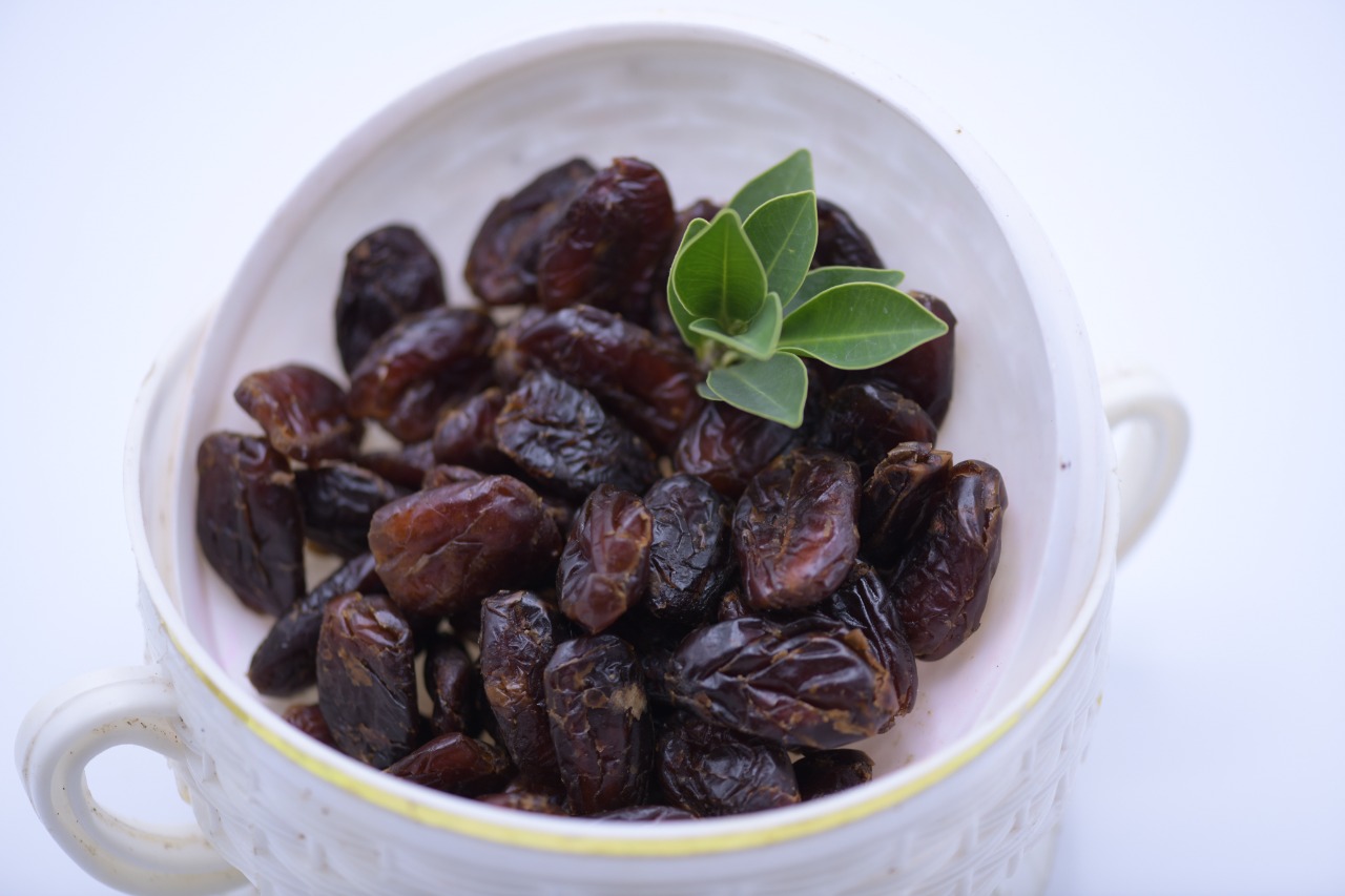 Dates served in a white cup with leaves